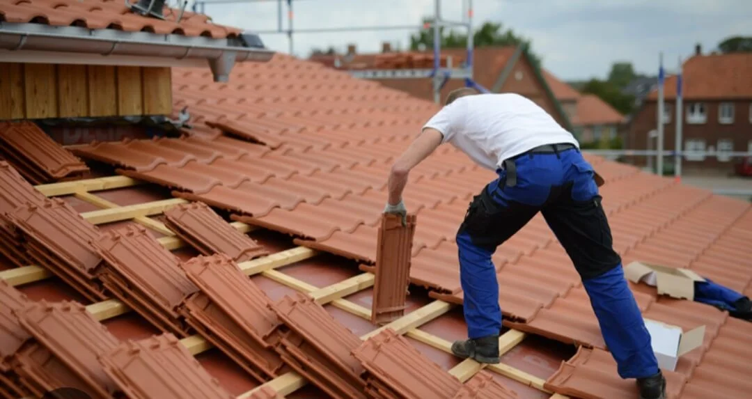 Couvreur professionnel posant des tuiles terre cuite sur un toit en pente en Provence