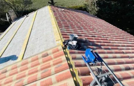 Travaux d’étanchéité : toit en tuiles partiellement découvert avec rouleau de membrane et outillage