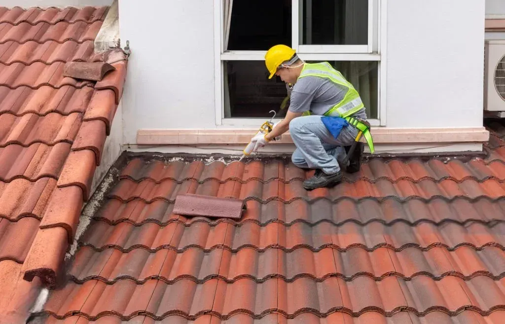 Couvreur fixant une gouttière en zinc le long d’un toit en tuiles pour assurer l’évacuation des eaux